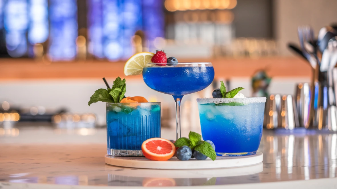 Collection of vibrant blue mocktails garnished with fresh fruits, showcasing various shades of ocean-inspired beverages