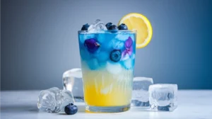 A stunning two-layer mocktail with deep blue butterfly pea tea floating on yellow lemonade, garnished with fresh blueberries and a lemon wheel