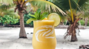 A smooth golden-yellow mango and coconut water mocktail garnished with fresh mint and a lime wedge