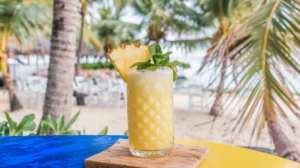 A sunny tropical pineapple mocktail garnished with a fresh pineapple wedge and mint leaves, served in a tall glass